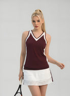 Woman wearing a maroon tank top with white lace trim and a white tennis skirt on a gray background